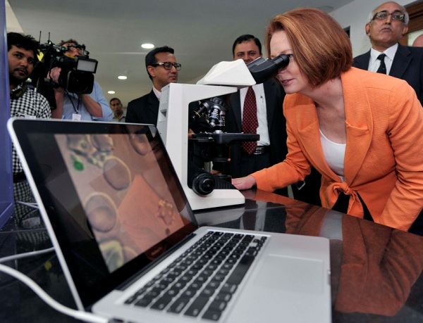 Prime Minister Julia Gillard looks through a microscope.